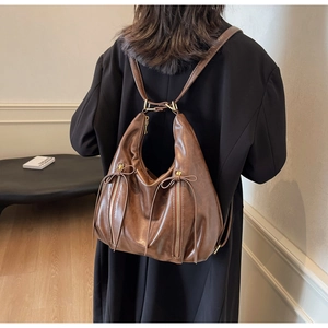 Rear view of a model wearing the brown vintage faux leather hobo backpack with zip details