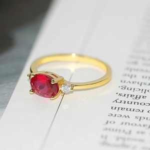 Elegant gold ring with an oval red ruby and sparkling side stones on a white page