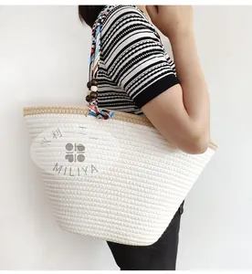 Detail of white cotton rope woven tote bag with geometric print scarf and wood beads