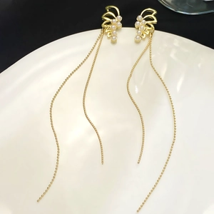 Detailed close-up of gold fringe tassel earrings with white pearls and fan-shaped design