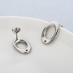 Boucles d'oreilles ovales minimalistes en acier inoxydable argenté sur un plat blanc