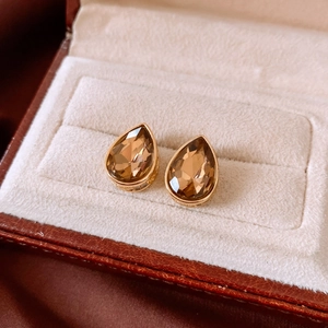 Macro view of gold teardrop earrings with amber zircon in a luxury jewelry box