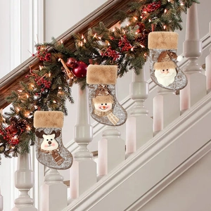Three Christmas stockings with sequins and 3D dolls hanging on a festive staircase railing