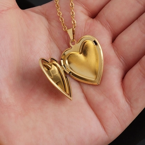 Close-up of an open heart-shaped gold photo locket necklace held in a hand