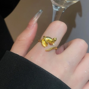 Detailed macro shot of a golden snake ring with scales on woman finger by a glass