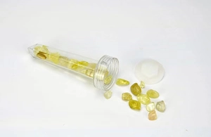 Detailed shot of open transparent tube filled with raw yellow crystal energy stones