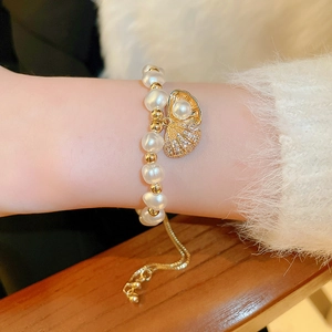 Detail of zircon shell and baroque pearl bracelet with adjustable gold chain on wrist