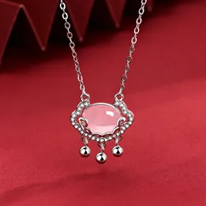 Macro detail of S925 silver Ruyi lock necklace with pink stone on red background