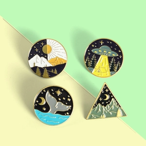 Detailed flat lay of four creative enamel brooches with whale tail and celestial designs