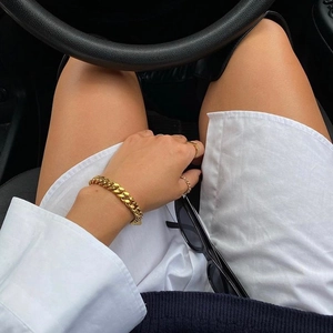 Close-up of 18k gold plated Cuban chain bracelet and ring set in a luxury car interior