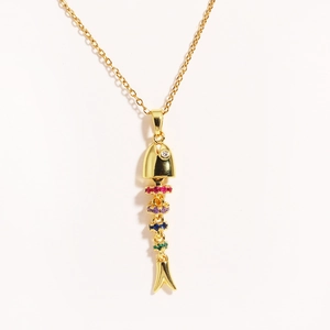 Detailed shot of a flexible fish skeleton pendant with colorful gemstones on a gold chain