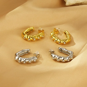 Close-up of vintage C-shaped gold and silver earrings with crystal stones on silk cloth