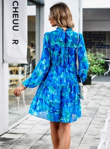 Détail d'une robe fleurie bleue avec col montant à volants et nœud papillon au dos