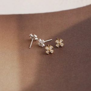 Macro view of flower stud earrings featuring marquise-cut zircons in silver and gold finish