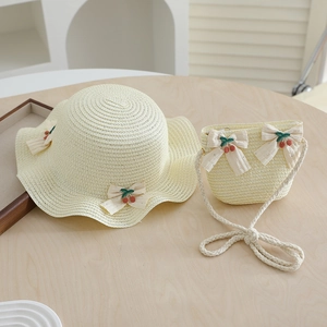 Détail du tissage en paille du chapeau de soleil et sac assorti avec nœuds cerise pour fille