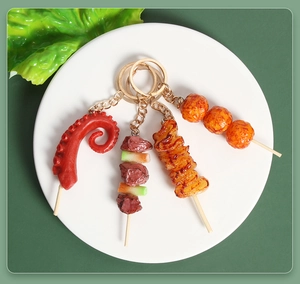 Set di 4 portachiavi realistici con spiedini alla griglia su piatto bianco con lattuga