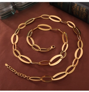 Macro shot of gold interlocking oval link necklace and bracelet set on brown fabric