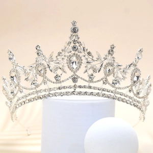 Detailed close-up of a silver vintage bridal crown with crystals on a white stand