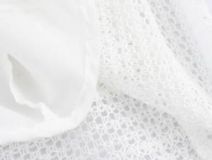 Macro shot of white mesh lace fabric texture and detailed hollow-out woven pattern