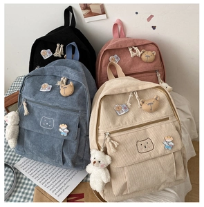 Detalle de cuatro mochilas de pana coloridas con colgantes de oso y pines bonitos