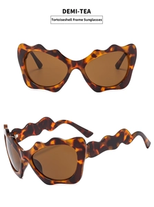 Detail of demi-tea Y2K cat eye sunglasses featuring unique wavy scalloped edge frames