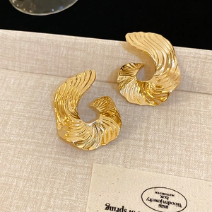 Macro detail of golden irregular geometric stud earrings with spiral textured pattern