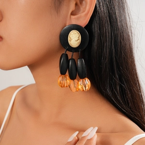 Close-up of vintage cameo drop earrings with black oval beads and amber sphere charms