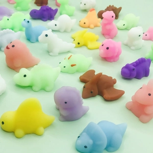 Colorful animal squishy toys in various dinosaur shapes for stress relief on green surface