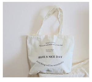 Close-up of beige canvas tote bag with black printed typography on a textured surface