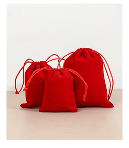 Three red velvet drawstring jewelry pouches in various sizes on a neutral background