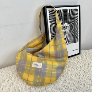 Detail view of yellow checkered canvas hobo bag texture and elegant brand fabric label
