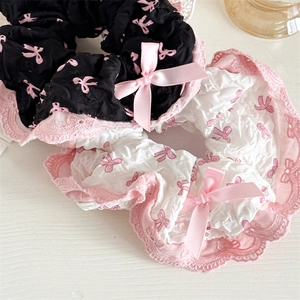 Detail of lace scrunchies in black and white with pink bows and ballet-style lace trims