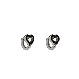 Détail de boucles d'oreilles cœur argentées avec émail noir sur un fond blanc propre