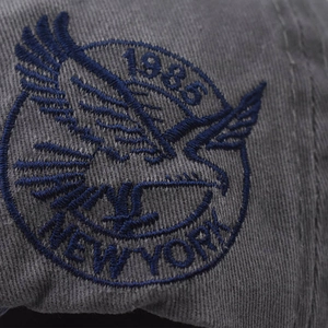 Detailed close-up of New York 1985 embroidery and eagle patch on gray vintage cotton cap