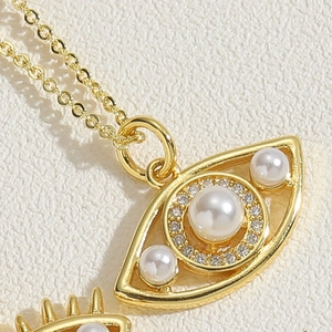 Macro shot of gold Evil Eye necklace with white pearls and sparkling zircon accents