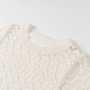 Detailed macro view of white crochet knit top showing intricate wave patterns and texture