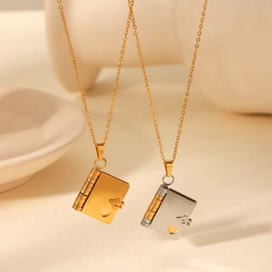 Close-up of heart-shaped book locket necklaces in gold and two-tone stainless steel