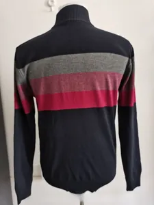 Detail of navy knit sweater featuring grey and red horizontal chest stripes and crew neck
