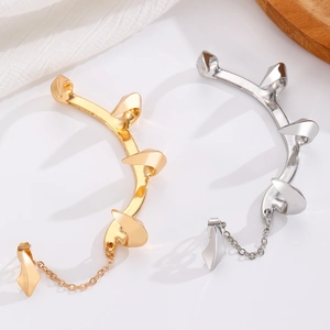 Close-up of punk style demon fang ear cuffs in gold and silver with metal chains