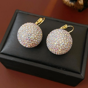 Close-up of gold spherical earrings set with colorful rhinestones on black texture