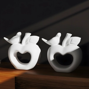 Artistic matte white apple bird sculpture with hollow heart detail on wooden table