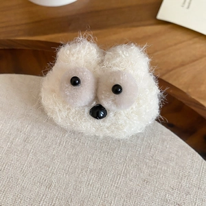 Macro shot of cute cream lamb wool monster brooch with grey eyes and plush texture