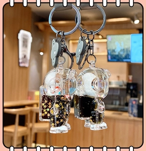 Detail of astronaut keychain with black liquid, golden stars and grey bear charm