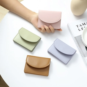 Minimalist short PU leather wallets in pink, green, purple, and brown shown on a desk
