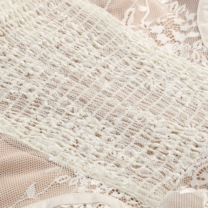 Detailed close-up of white floral lace texture and pleated elastic fabric on dress