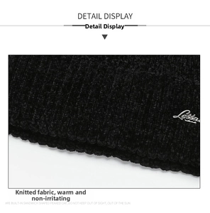 Close-up of black ribbed knit beanie featuring a metallic silver cursive letter emblem