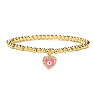 Detailed macro of gold beaded bracelet with pink enamel evil eye heart charm and zircons