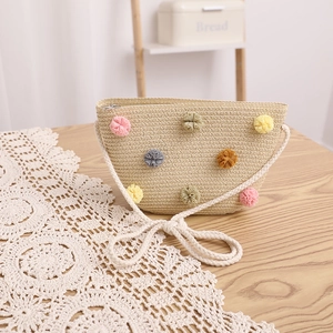 Detail of straw bag with colorful pom-poms, zipper closure and braided rope strap