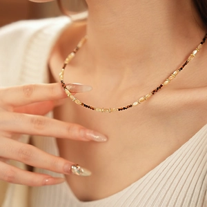 Détail du collier de perles en nacre avec perles marron et beige porté par un modèle