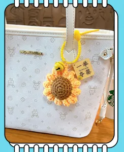 Crochet sunflower keychain with first prize tag hanging on a stylish white tote bag.
